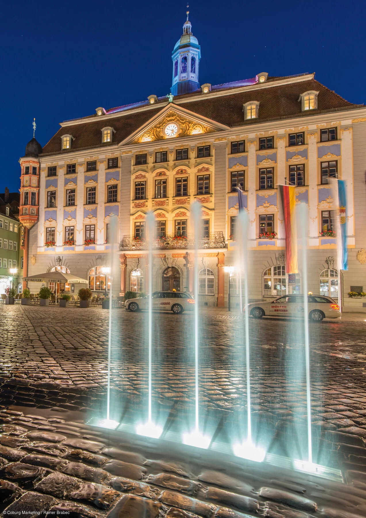 Marktplatz mit Rathaus und Fontäne bei Nacht
