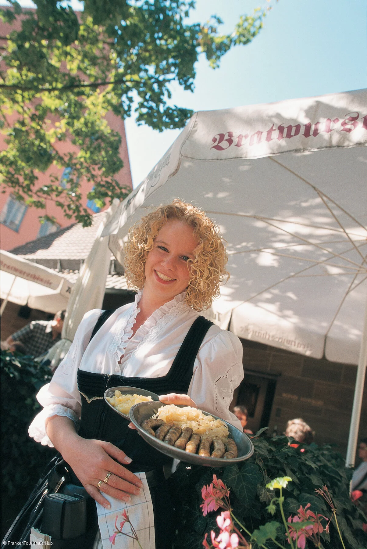 "Bratwursthäusle", Kellnerin Yvette Becher mit Bratwürsten auf Kraut