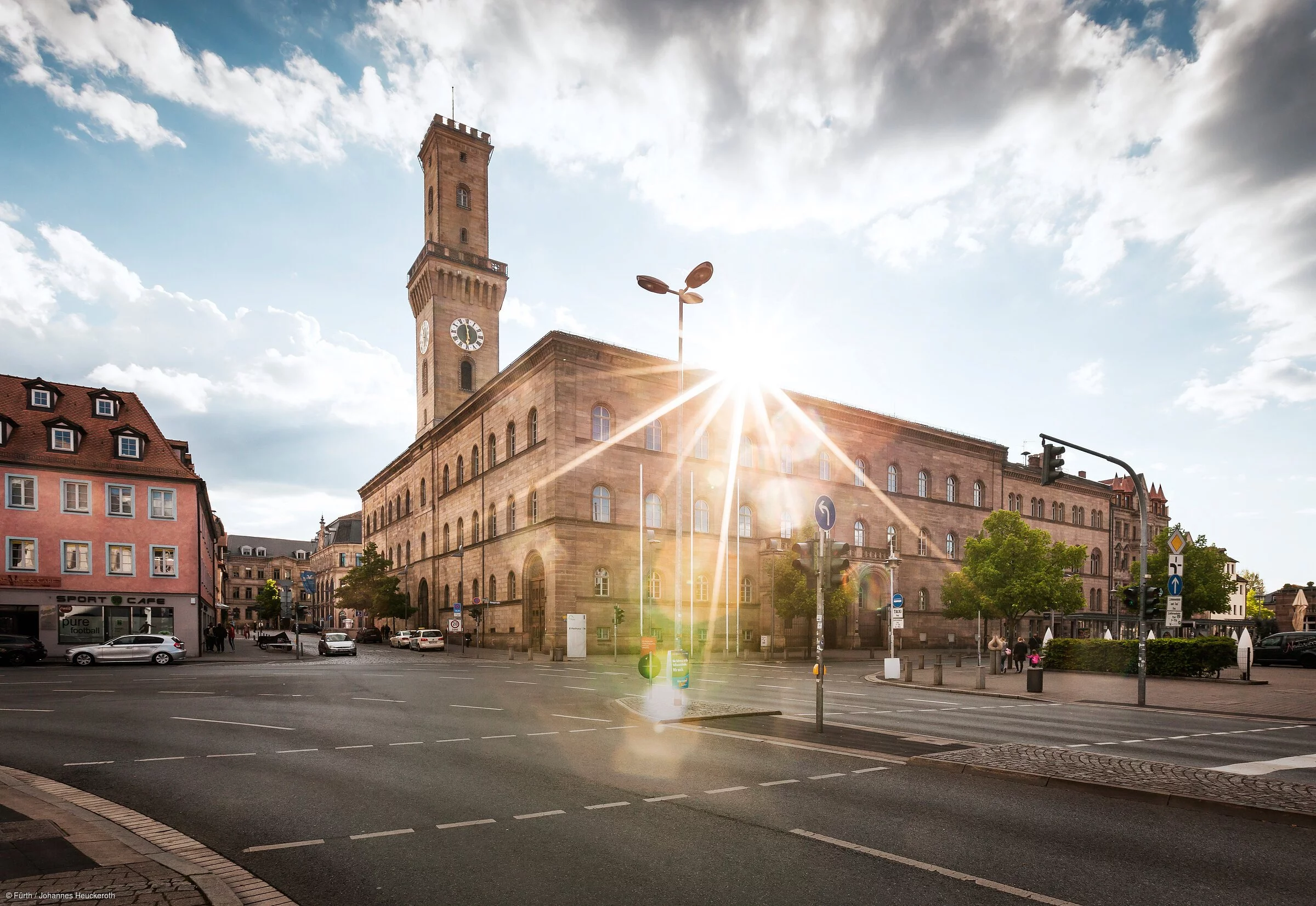 Ein repräsentatives Gebäude mit einem Turm, hinter dem gerade die Sonne aufblitzt