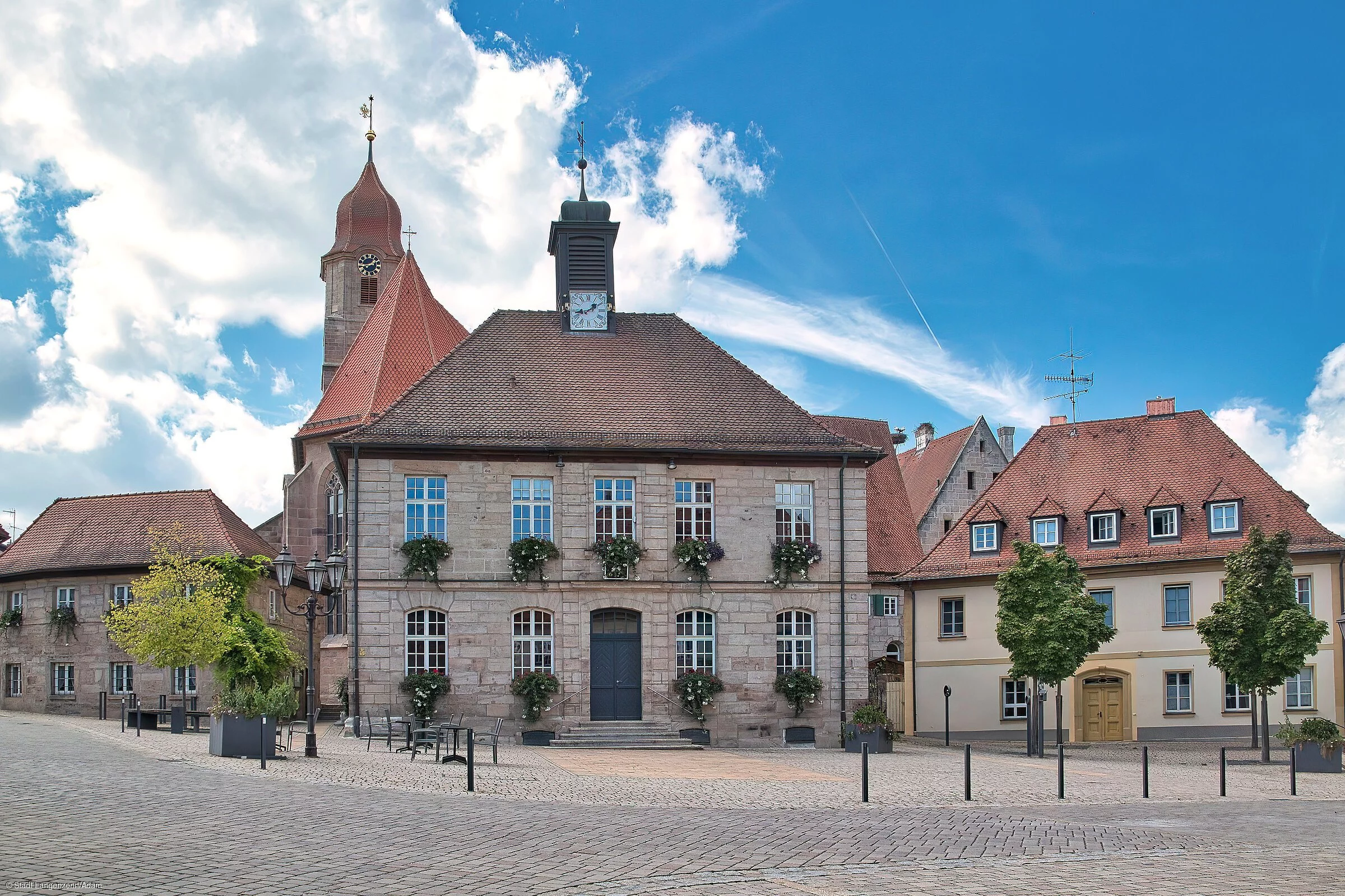Ein Marktplatzensemble mit Rathaus und Kirchturm in rötlichem Sandstein