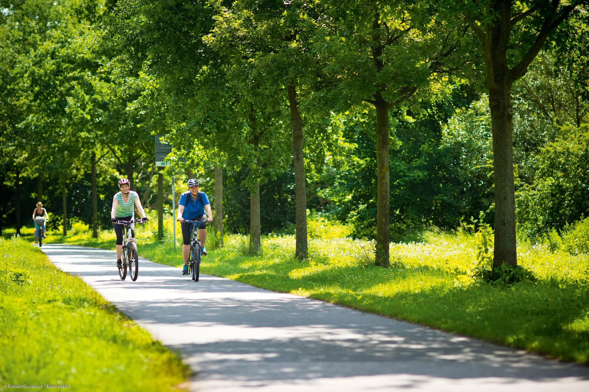 Zwei Radfahrende fahren auf einem Radweg im Grünen