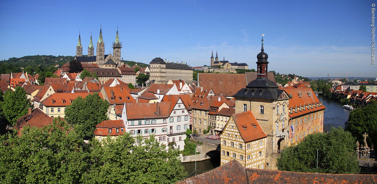 Bei bestem Wetter Blick über eine bunte, mittelalterliche Altstadt mit Türmen und roten Dächern